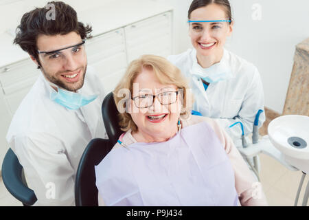 Dentisti e paziente in chirurgia guardando la fotocamera Foto Stock