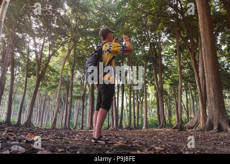 Maschio passeggiate turistiche in joungles e rendendo le foto durante il viaggio eccitato in Asia la foresta di legno.esperto viaggiatore fotografare esplorare veget verde Foto Stock