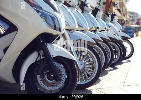 Fila di scooter in vendita e in affitto su strade. Foto Stock