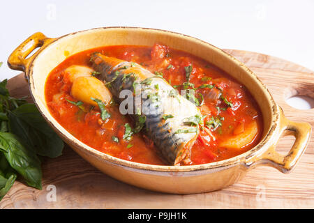 Grigliata di sgombri che sono state collocate su una patata, la cipolla e la base di salsa al pomodoro con erbe miste e guarnite con foglie di basilico. Gli sgombri sono stati catturati sh Foto Stock