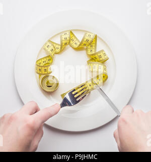Concetto di dieta, nastro di misurazione appare come la pasta mettere sulla forcella, su sfondo bianco, perdere peso Foto Stock