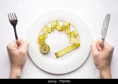Concetto di dieta, nastro di misurazione appare come la pasta mettere sulla forcella, su sfondo bianco, perdere peso Foto Stock