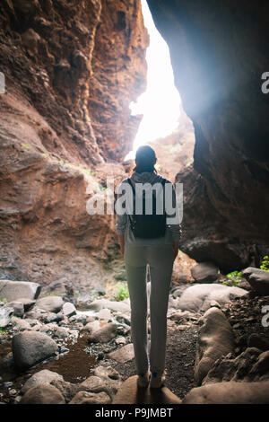 Silhouette di donna di viaggiatori nella grotta di montagna. La luce alla fine della grotta Foto Stock