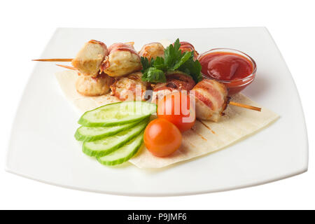 Pollo su uno spiedino, cotta in pancetta, poggia su una pita con cucumb Foto Stock