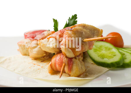 Pollo su uno spiedino, cotta in pancetta, poggia su una pita con cucumb Foto Stock