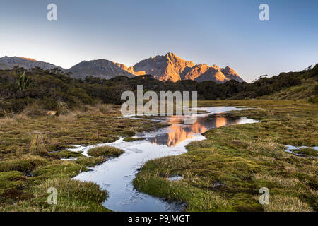 Ailsa montagne riflette in stagno sul Vertice di chiave in atmosfera serale, la gamma della montagna del Parco Nazionale di Fiordland Southland, Foto Stock