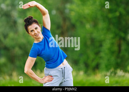 Senior donna che esercitano nel parco. Femmina anziani facendo esercizi fitness all'aperto. Heathy stile di vita concetto. Copyspace. Foto Stock