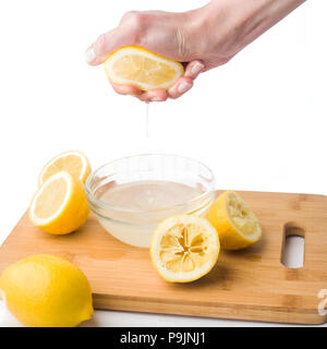 Mano spreme il succo di limone su uno sfondo bianco, isolato Foto Stock
