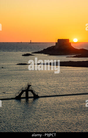 Il sole che tramonta dietro le Petit essere isola, di fronte alla città di Saint-Malo con il sewater pool di Bon Secours beach e la sua piattaforma subacquea. Foto Stock