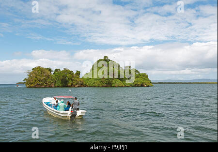 Cayo o isola di roccia, fregate cerchio sopra, barche a motore davanti e dietro, Parco Nazionale Los Haitises, Samaná Provincia Foto Stock