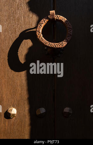 Ferro battuto respingente porta su una tavola di legno porta anteriore Pyreneean vilage og generano, Catalogna, Spagna Foto Stock