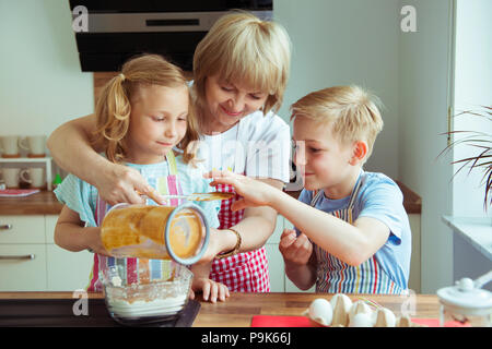 Nonna felice con i suoi nipoti avendo divertimento durante la cottura i muffin e i cookie Foto Stock