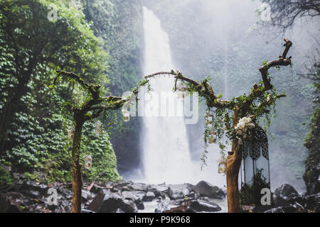 Tropical cerimonia di nozze con cascata vista nella giungla canyon. Decorate con verde edera, antiche filiali e lampade pensili Foto Stock