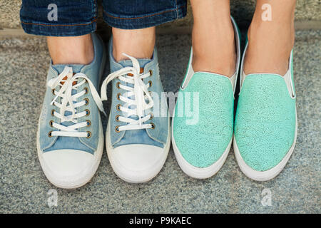 Due coppie di ragazza in piedi in sneakers Foto Stock