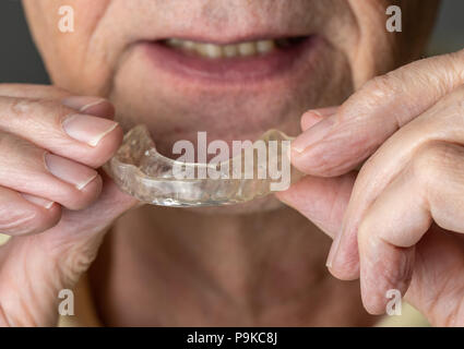 Senior uomo mettendo una guardia notturna su denti storti Foto Stock