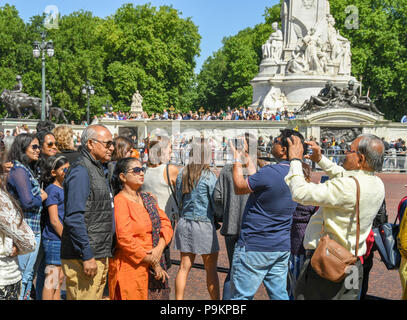 I turisti a scattare foto di altre persone nel loro tour delle parti al di fuori Buckingham Place Foto Stock