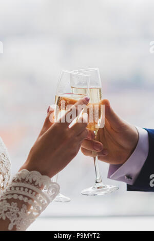 L uomo e la donna mani due bicchieri di champagne decorato con fiori per la cerimonia di nozze Foto Stock