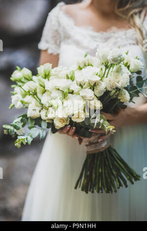 Sposa tenendo in mano grande mazzo di rose bianche Foto Stock