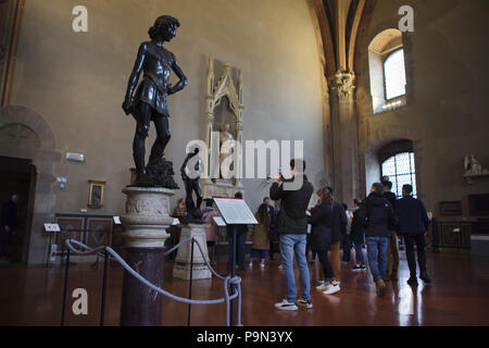 I visitatori di fronte alla statua di bronzo del David dal Rinascimento italiano scultore Andrea del Verrocchio datata da ca. 1466-1469 visualizzato nel Museo del Bargello (Museo Nazionale del Bargello di Firenze, Toscana, Italia. Statua di bronzo del David dal Rinascimento italiano scultore Donatello è visto in background. Foto Stock