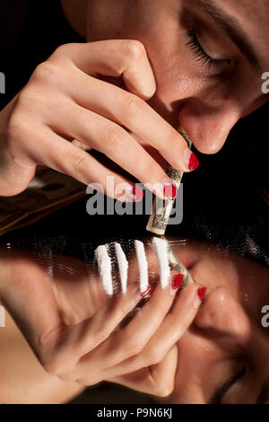Un giovane tossicodipendenti sniffles donna le linee di polvere bianca sul mirror Foto Stock