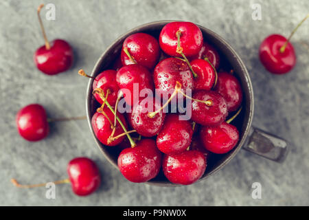 Vista dall'alto di una ciotola con ciliegia matura su sfondo grigio. Il concetto di sano cibo biologico. Foto Stock