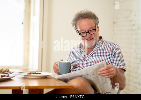Ritratto di felice senior vecchio uomo con i capelli grigi leggendo il giornale mentre si consuma la colazione e bere un caffè in buona vecchiaia concetto di pensionamento Foto Stock