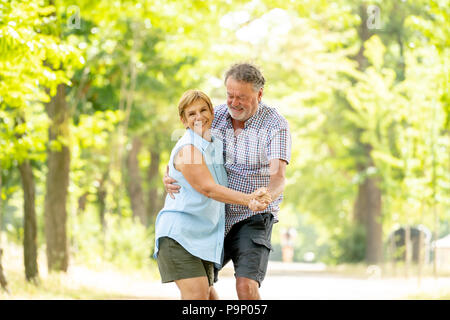 Sorridenti coppia senior in amore, ballare e divertirsi nel parco. Essendo, insieme nell'amore, il pensionamento felice vita concetto. Foto Stock