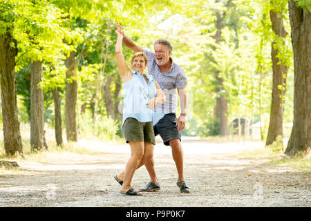 Sorridenti coppia senior in amore, ballare e divertirsi nel parco. Essendo, insieme nell'amore, il pensionamento felice vita concetto. Foto Stock