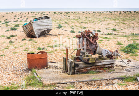 Abbandonata la pesca in legno barca e motore arrugginito sul foreshore della spiaggia di ciottoli a Dungeness, Shepway district, Kent Foto Stock
