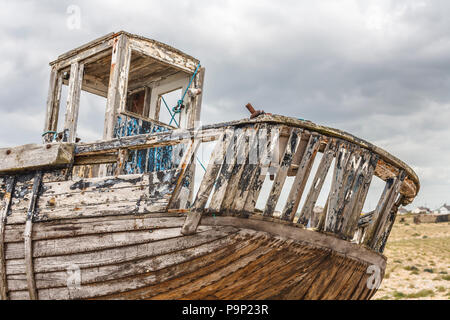 La poppa di un marciume, disintegranti in legno barca da pesca falling apart sul foreshore della spiaggia di ciottoli a Dungeness, Shepway district, Kent Foto Stock