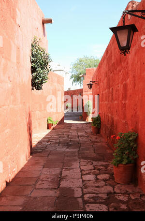 Stretta strada di ciottoli tra i vivaci colori arancione di vecchi edifici nel monastero di Santa Catalina Arequipa, Perù Foto Stock