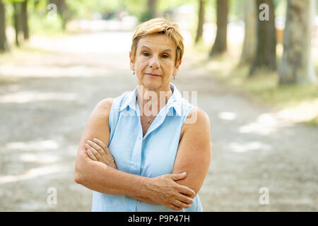 Emozione, età e persone concetto - Ritratto di una bella donna senior nel parco alla ricerca seria e premurosa verso la telecamera Foto Stock