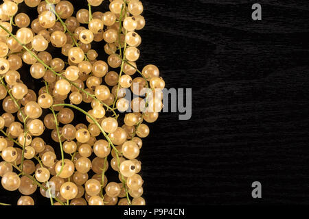 Sacco di intero fresco Ribes bianco berry blanka varietà sinistra flatlay sul legno nero Foto Stock