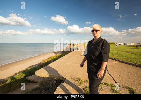 La donna si innalza accanto al bordo del collasso Rupi costiere a Aldbrough Yorkshires sulla costa est, UK. Ella si fermò nella posizione in cui il suo uso interno Foto Stock