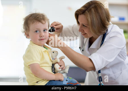 Medico esamina orecchio con otoscopio in un pediatra camera. Apparecchiature mediche Foto Stock