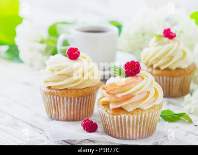 Delicati tortini alla vaniglia con crema di lamponi e su un bianco sullo sfondo di legno Foto Stock