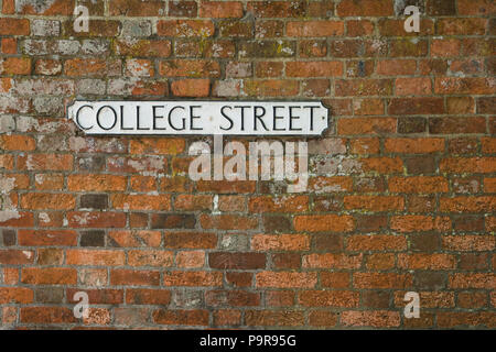 College Street su una strada bianca nome sign impostato su in rosso di un muro di mattoni. Foto Stock