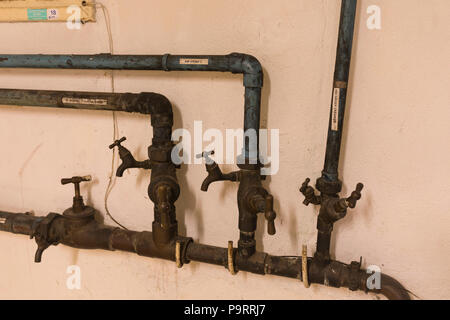 Tubi di acqua e prese appartenenti al vecchio edificio Foto Stock