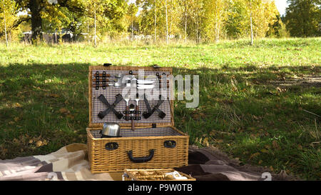 Cesto in legno per un picnic con piastre. Cestello per un picnic nel parco in una giornata di sole. Picnic esterno alla giornata di sole. Foto Stock