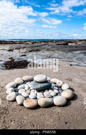 Rock cataste o pile in formazione circolare design cerchi cerchio su una spiaggia Foto Stock