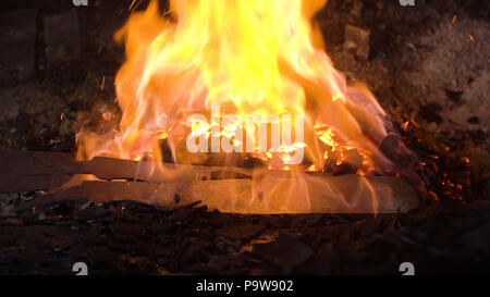 Fabbro forno con un ferro caldo, brace ardente, scintille. Fornace di fuoco ardente con la combustione di carbone in corrispondenza del fabbro. Fabbri rendere machete. Filippine. Foto Stock