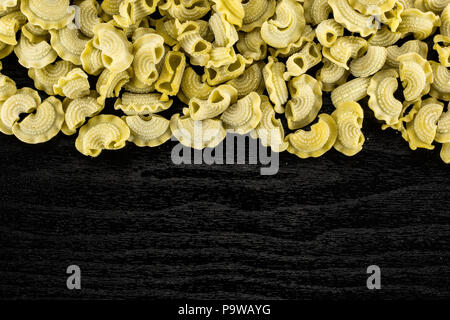 Pasta spinaci creste di gallo flatlay isolato nero su uno sfondo di legno vista superiore materie Foto Stock