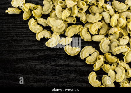 Pasta spinaci creste di gallo flatlay grezzo isolato nero su uno sfondo di legno vista superiore Foto Stock