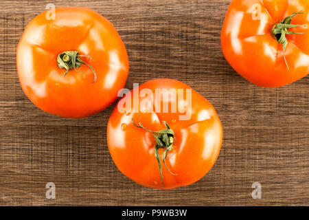 3 pomodoro rosso isolato su legno marrone sfondo vista superiore Foto Stock