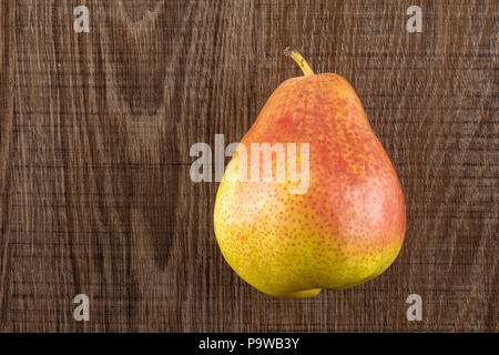 Un intero fresco rosso forelle pear varietà flatlay su legno marrone Foto Stock