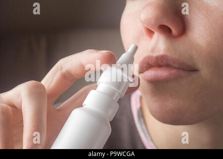 Una donna con un naso che cola detiene una medicina in mano un rosso n. Foto Stock