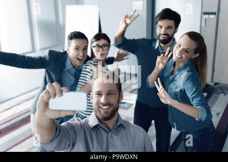 L'atmosfera cordiale. Gioioso sorridente giovani colleghi che fanno selfies e di stare in ufficio durante una pausa Foto Stock
