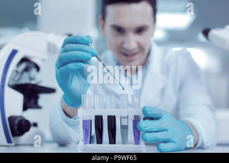 La ricerca medica. Messa a fuoco selettiva di tubi in piedi in rack nel laboratorio medico mentre viene usata per la ricerca medica Foto Stock