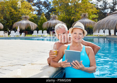 Coppia senior utilizzando computer tablet in hotel Piscina durante una vacanza wellness Foto Stock