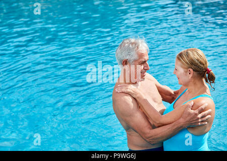 Coppia senior in piscina guarda in amore con gli occhi in vacanza estiva Foto Stock